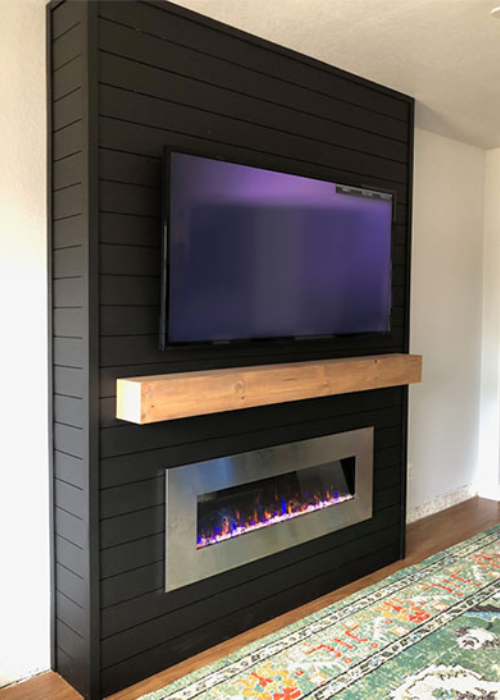 Black TV unit with built-in fireplace and wooden shelf.