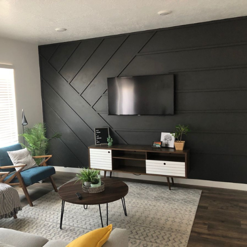 Modern living room with black accent wall and TV.