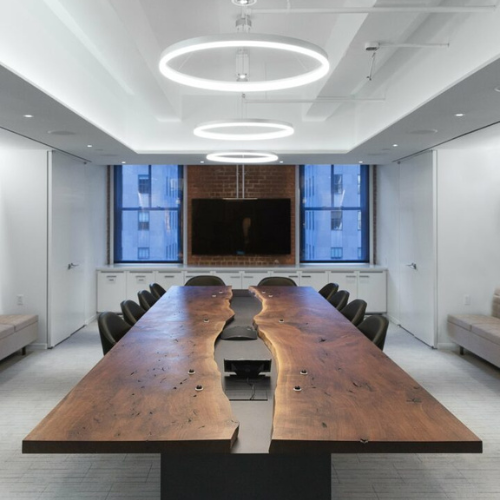 Sleek conference room with a large wooden table and circular lights.