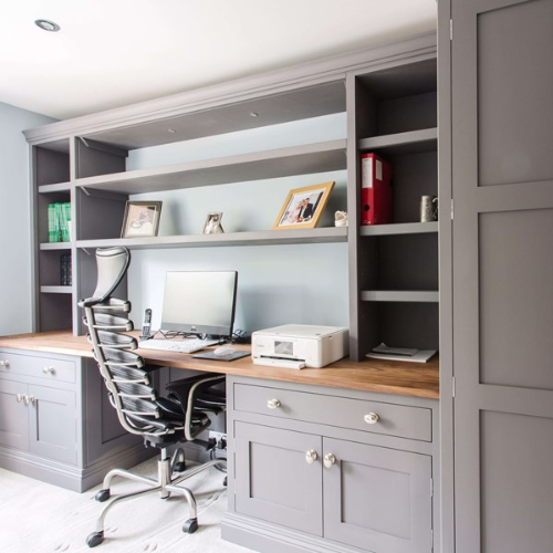 Modern home office with built-in gray shelving and desk.