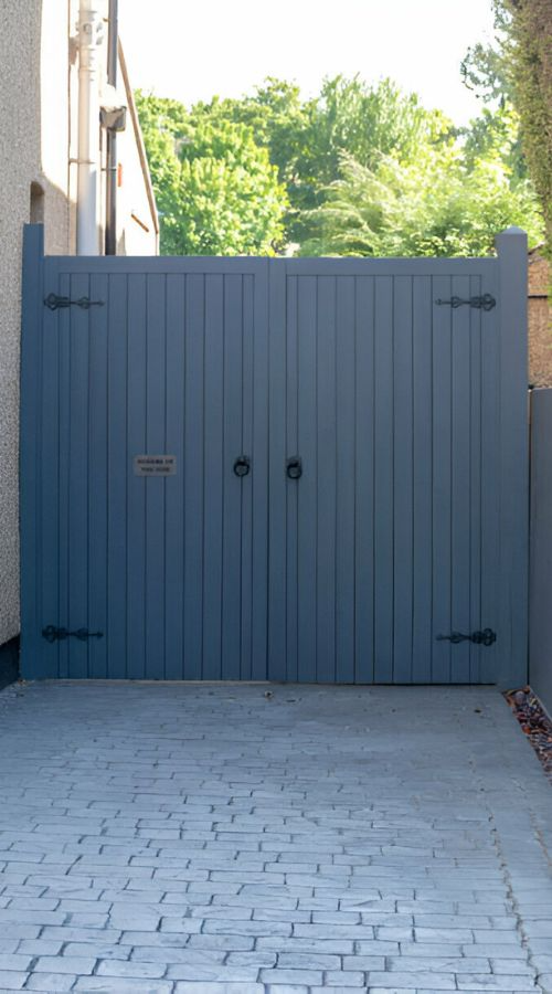 Contemporary wooden driveway gate with horizontal planks and modern lighting.