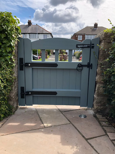 Grey wooden gate with black hinges and ring pull.