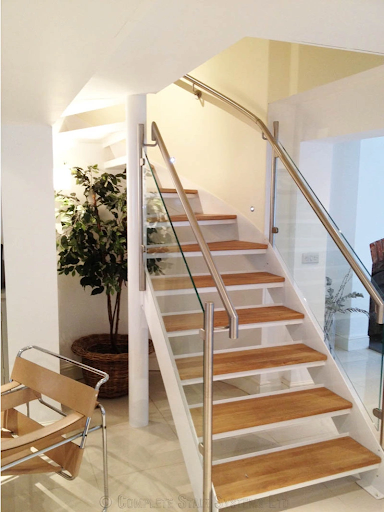 Contemporary wooden staircase with glass railings and stainless steel accents