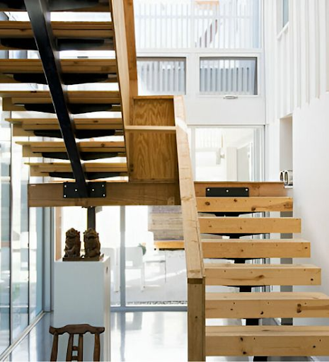 Modern wooden staircase with open risers and black metal supports in a bright interior