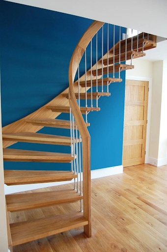 Elegant spiral wooden staircase with blue accent wall.