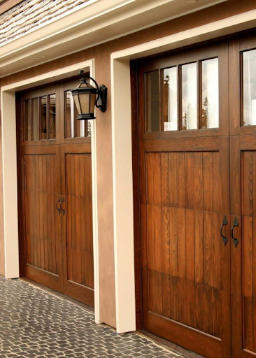 Double wooden garage doors with black lanterns.